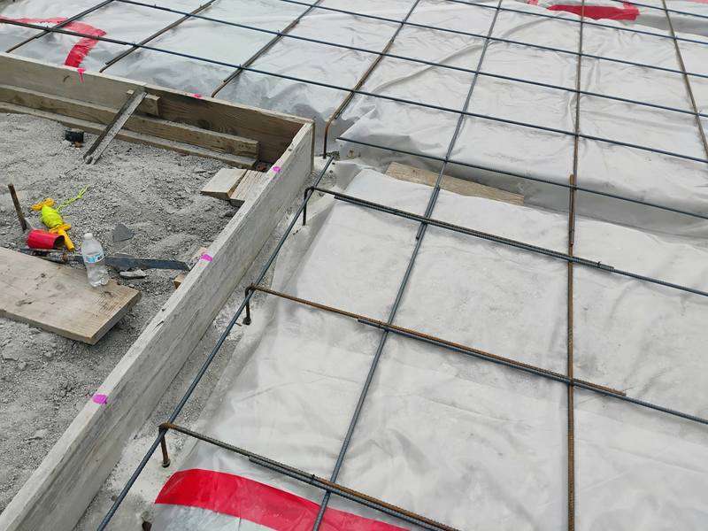 Rebar grid and vapor barrier set over a formed slab before the pour
