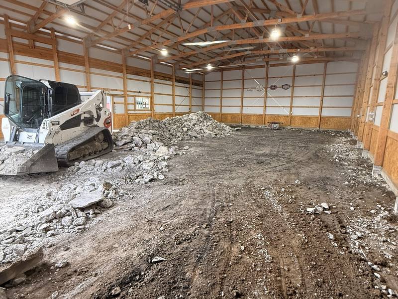 Skid steer grading and packing the base inside a new pole barn