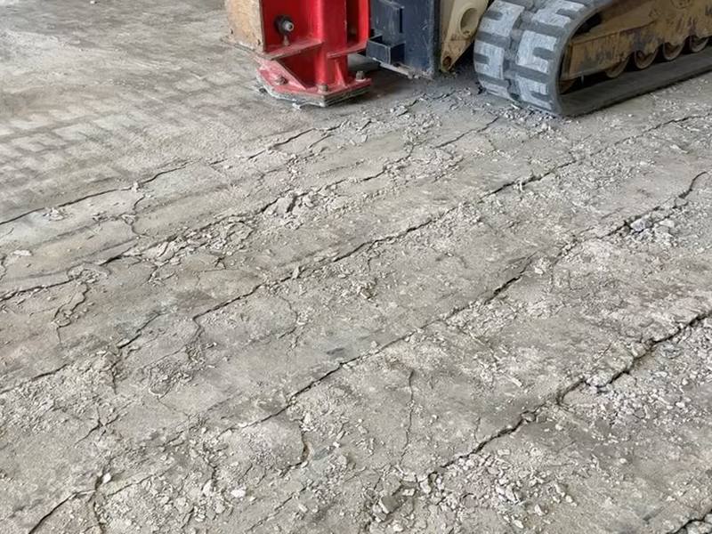 Skid steer with attachment preparing and compacting the gravel base