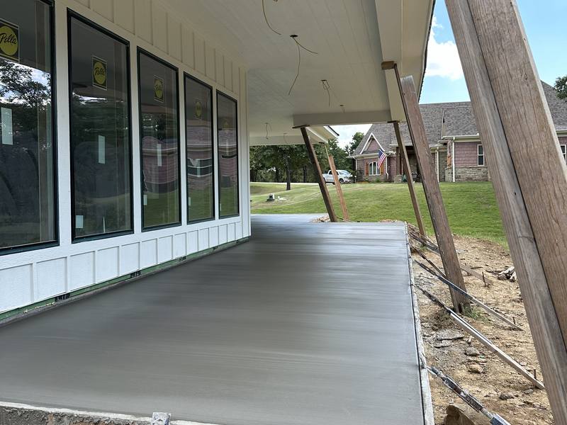 Newly poured covered patio slab along the back of a home