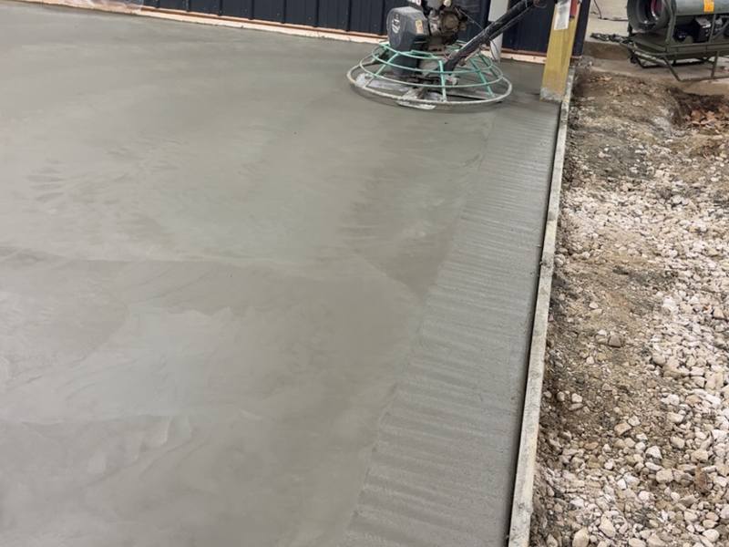 Freshly poured shop slab finished alongside a metal building